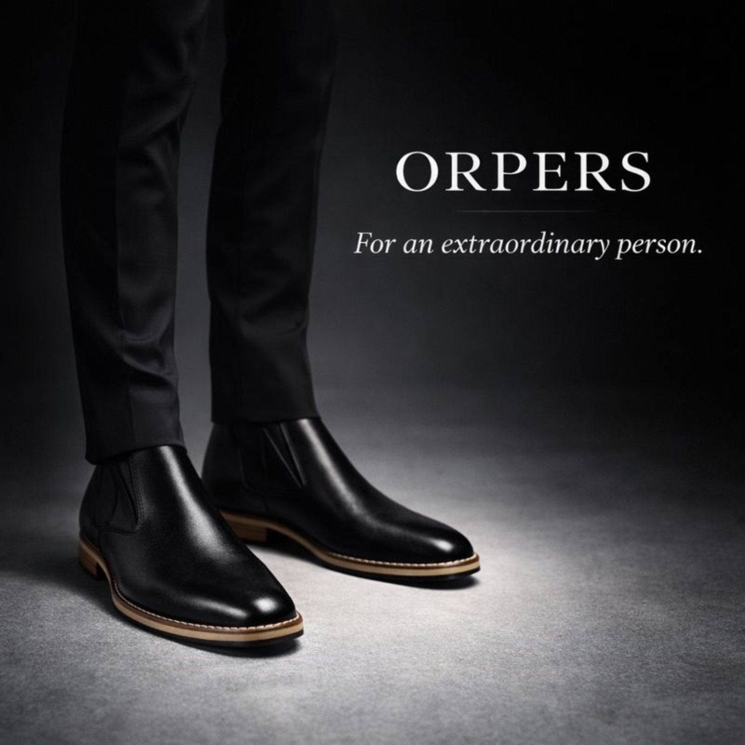 Man wearing black ORPERS Chelsea boots with polished leather finish and tan welt detail, standing in a dark studio setting with brand tagline visible.
